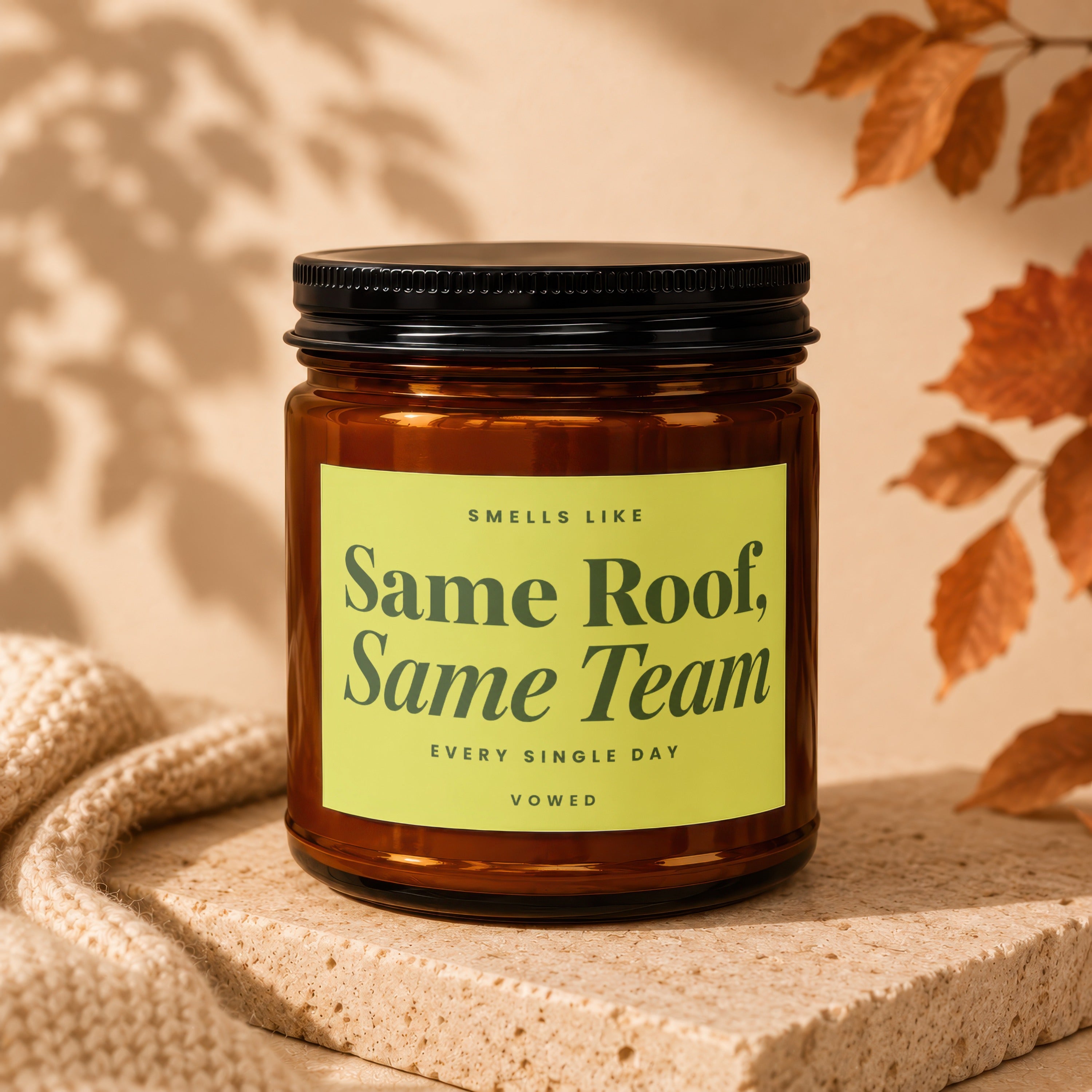Amber candle with black lid, green label reading "Same Roof, Same Team, Every Single Day, Vowed".
