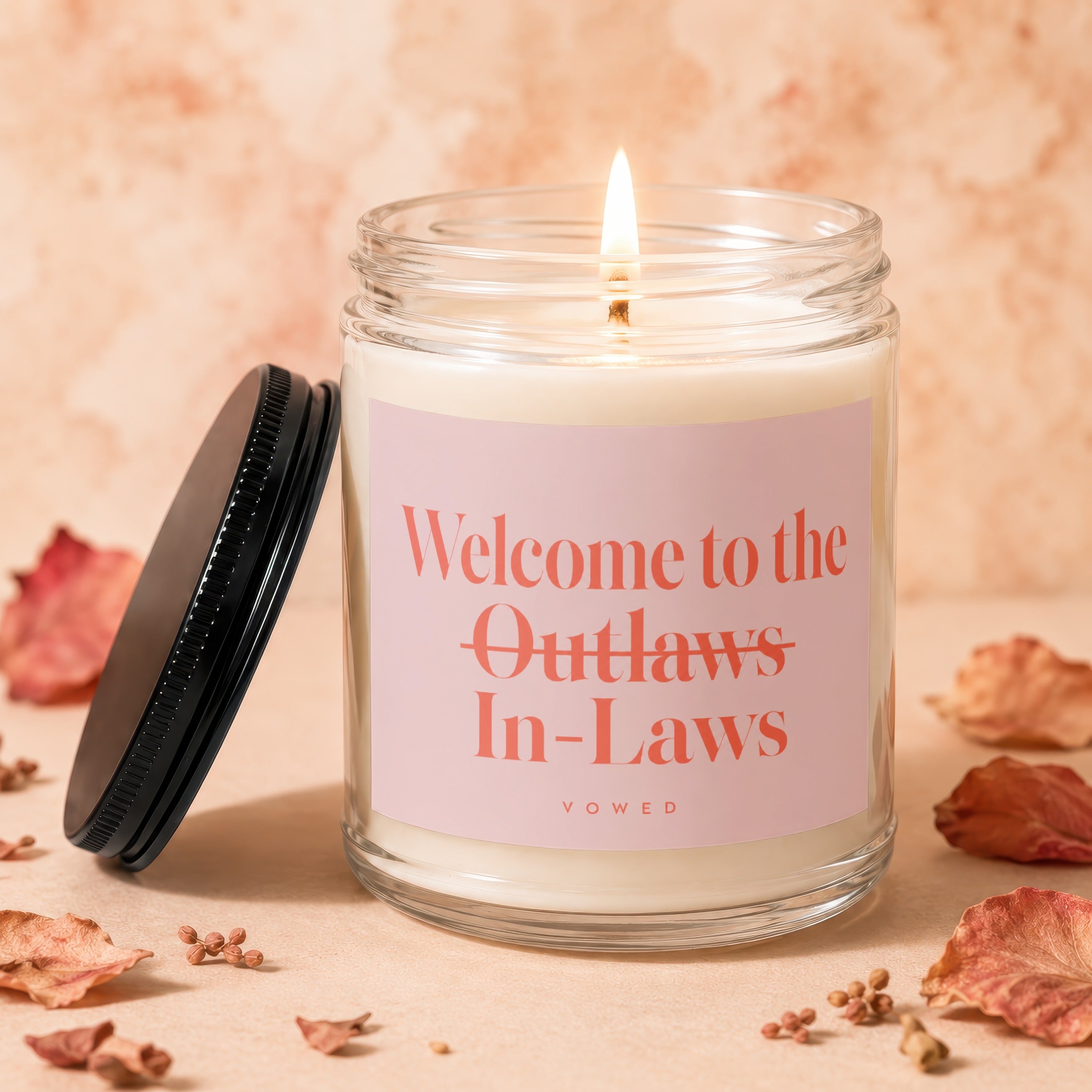 Jar candle with pink label reading "Welcome to the Outlaws In-Laws" and "vowed."