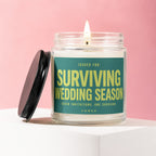 Candle with "Surviving Wedding Season" text, seven invitations, one survivor.