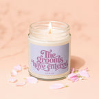 Candle with "The grooms have entered" text and pink petals on peach background.