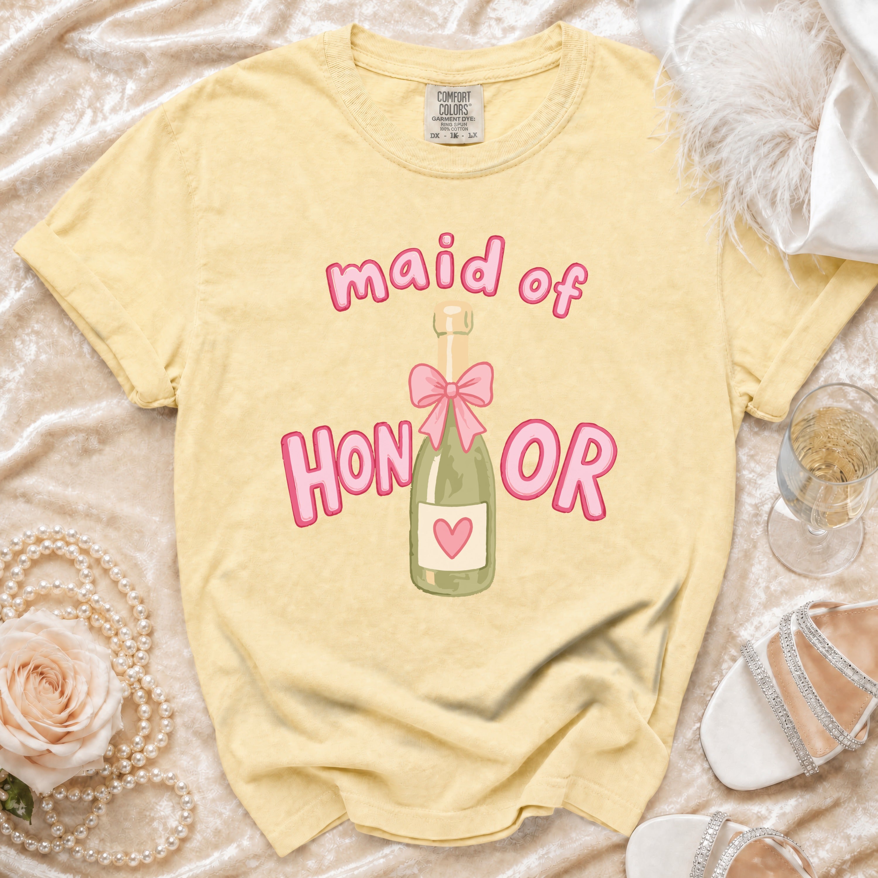 Yellow t-shirt with pink "maid of honor" text and champagne bottle graphic.