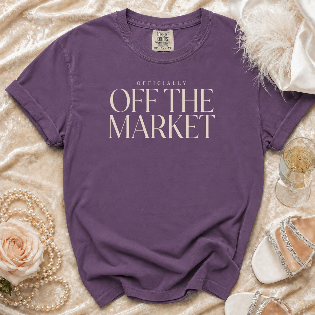 Purple t-shirt with "OFFICIALLY OFF THE MARKET" text, arranged with pearls and a rose.