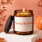 Brown glass candle with lit wick says "Married My Person" and "Vowed".