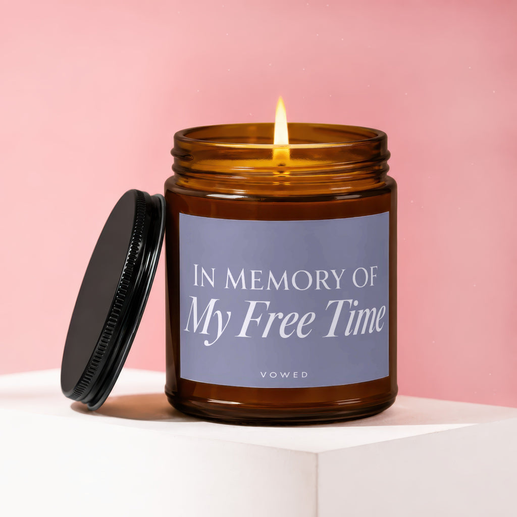 Amber glass candle with lit wick and black lid, reading "In Memory Of My Free Time"