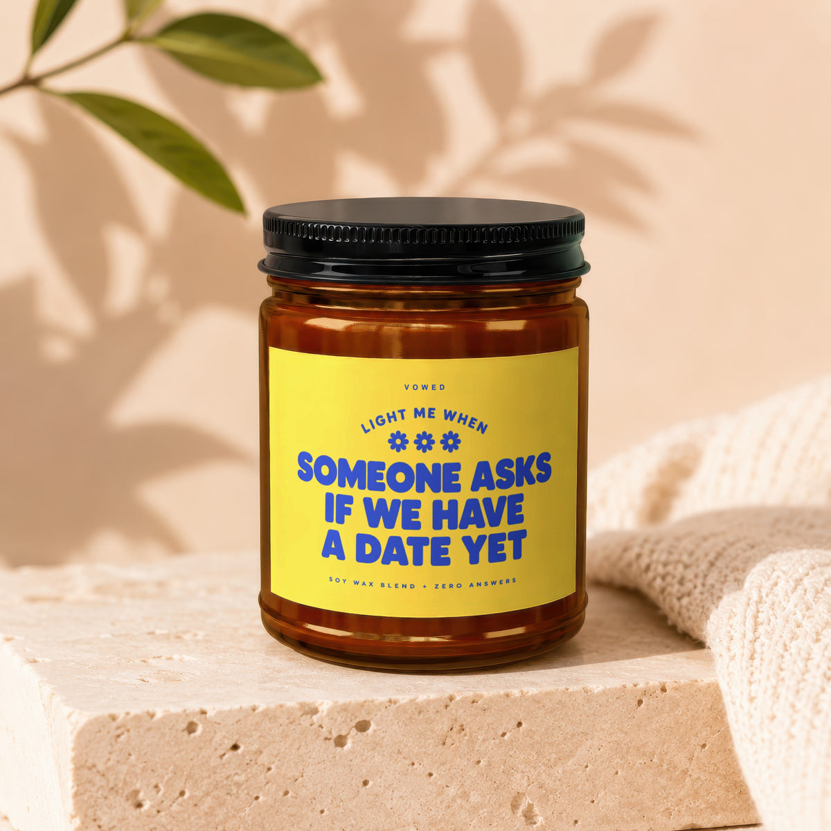 Amber jar candle with yellow label reading "Light me when someone asks if we have a date yet".