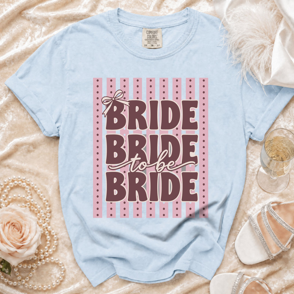 Light blue t-shirt with "BRIDE to be BRIDE" text and pink stripe background.