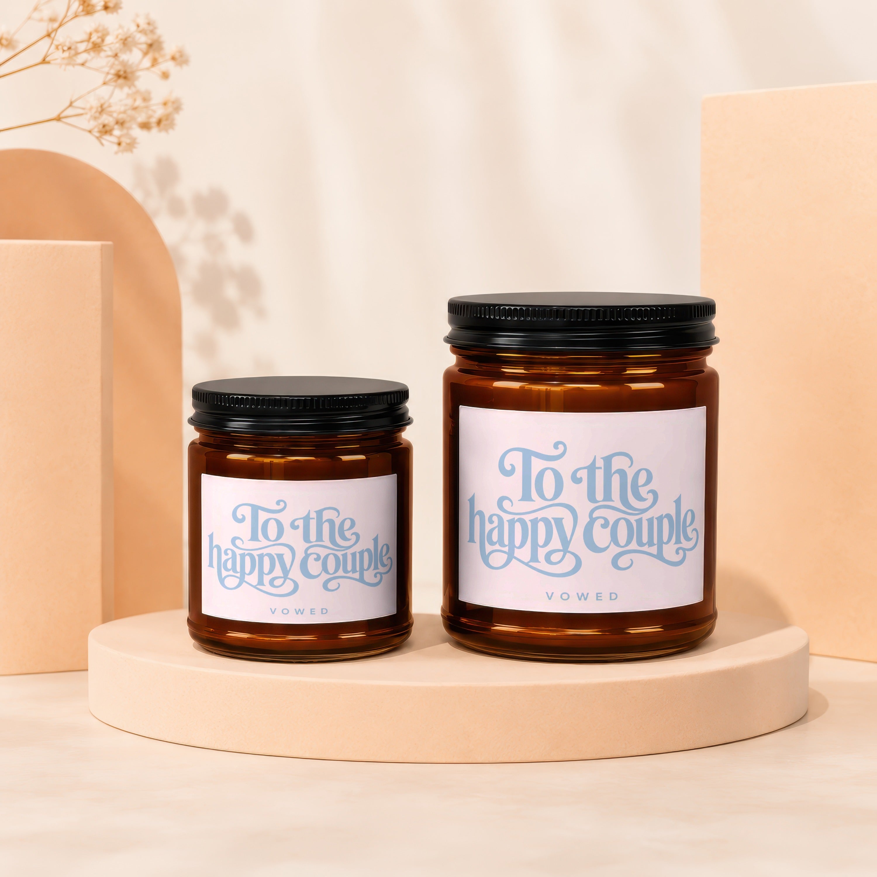 Two amber glass candles with black lids, labeled "To the happy couple" and "Vowed".
