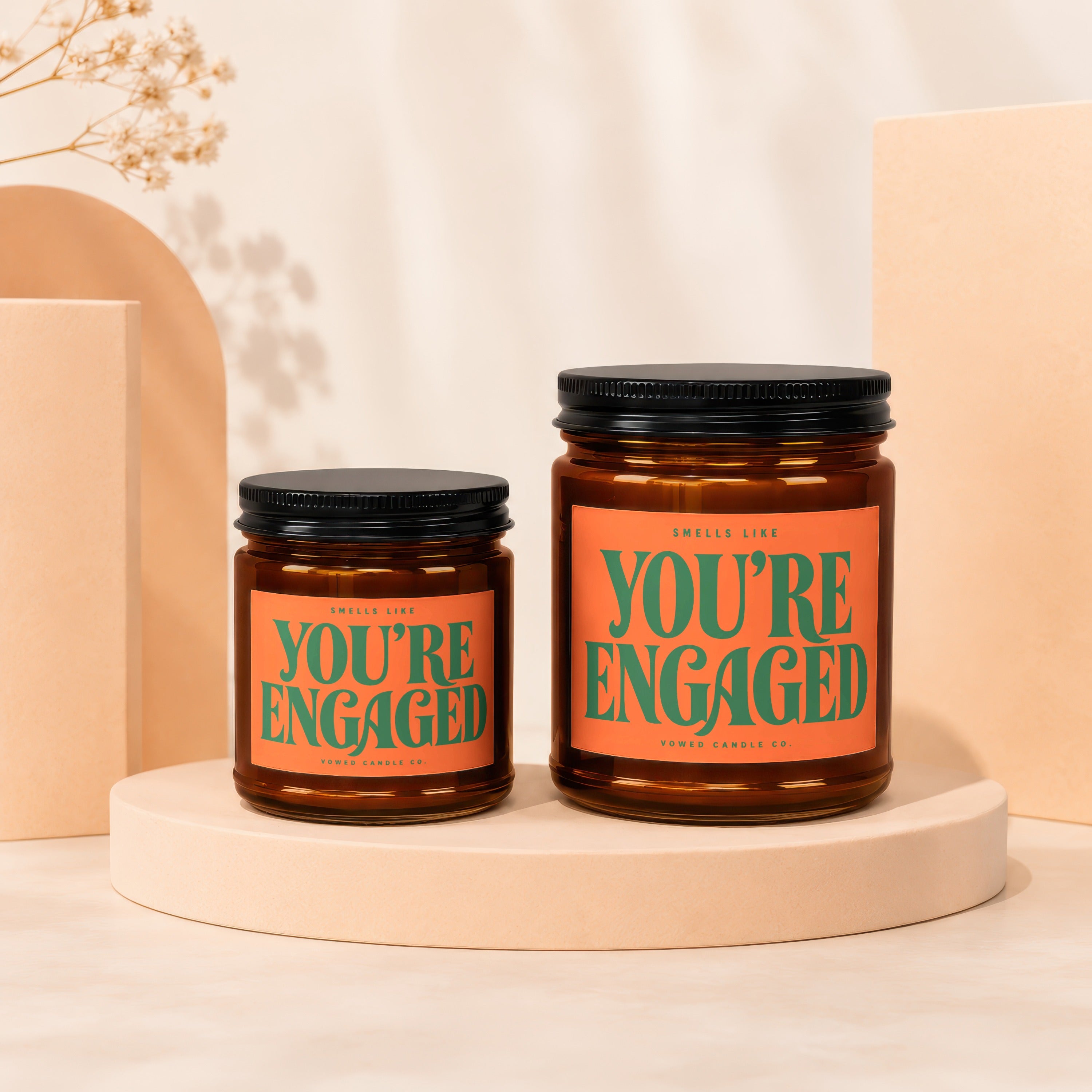 Two amber glass candles with labels reading "Smells Like You're Engaged".