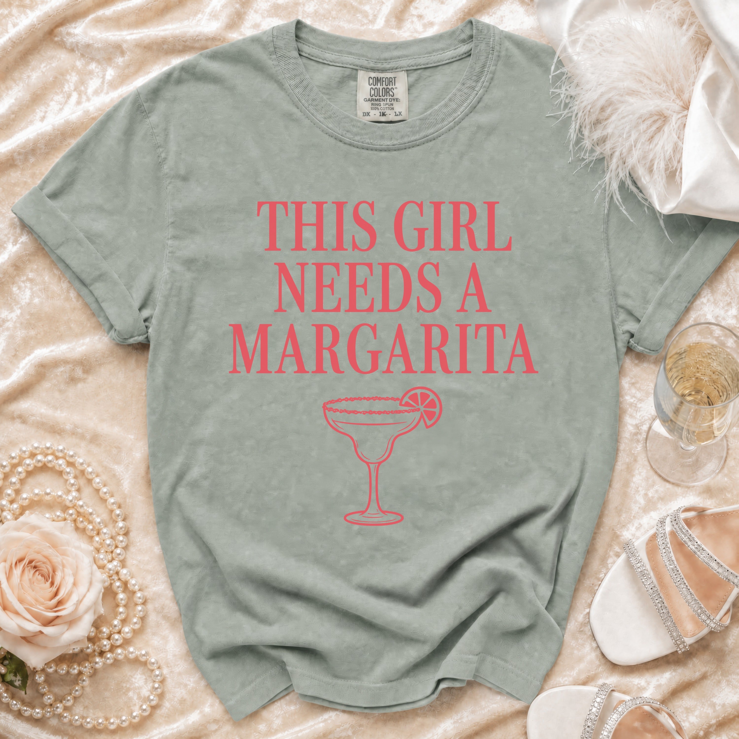 A sage graphic tee with "THIS GIRL NEEDS A MARGARITA" and a margarita glass.