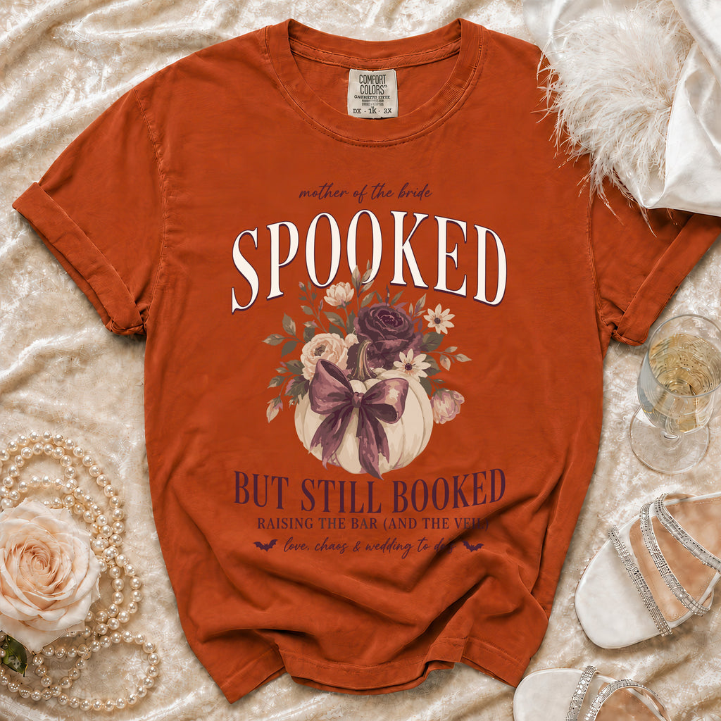 Orange t-shirt for mother of the bride, "Spooked But Still Booked" text with pumpkin.