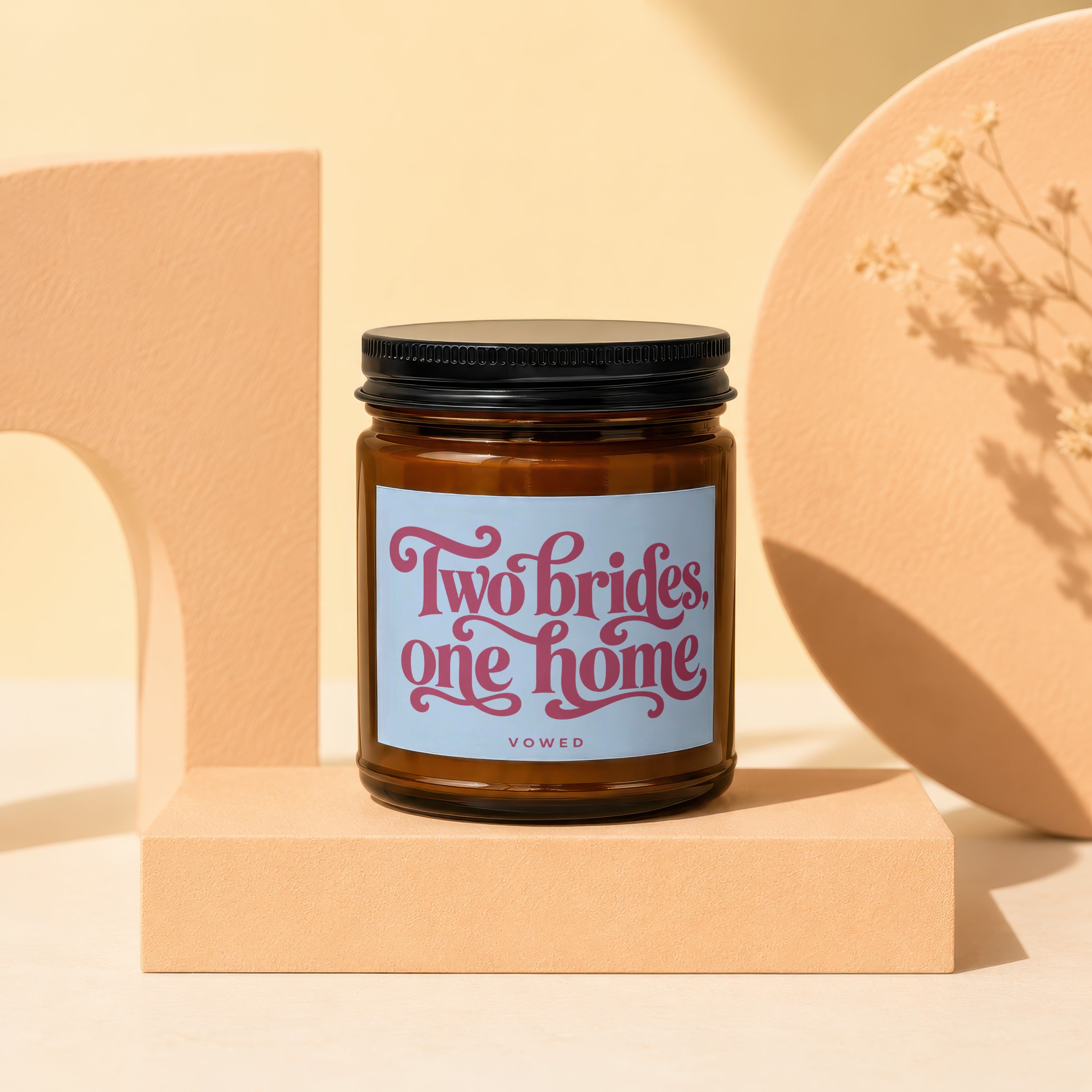 Amber jar candle with a light blue label reading "Two brides, one home VOWED."