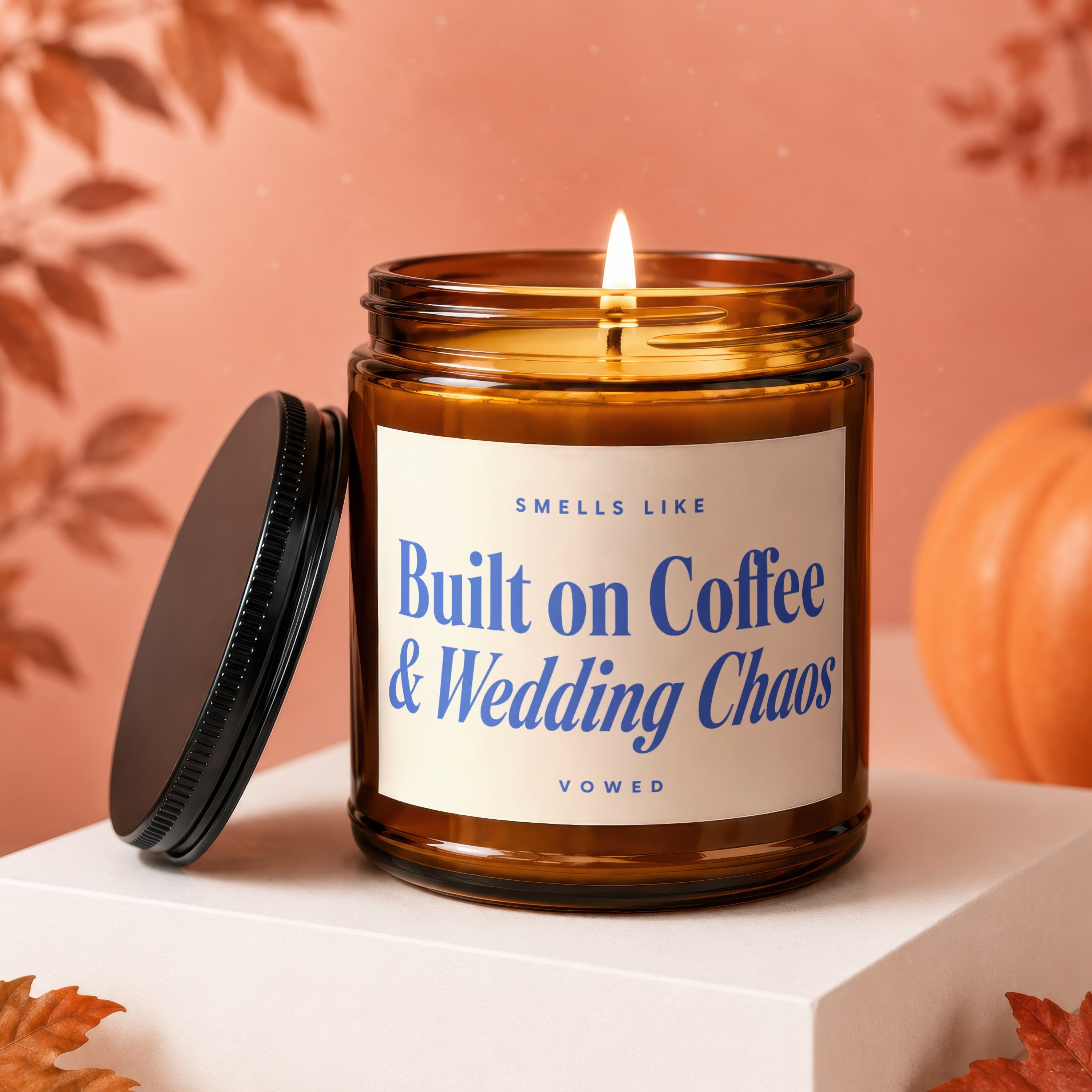 Amber candle with lit wick, says "Smells Like Built on Coffee & Wedding Chaos".