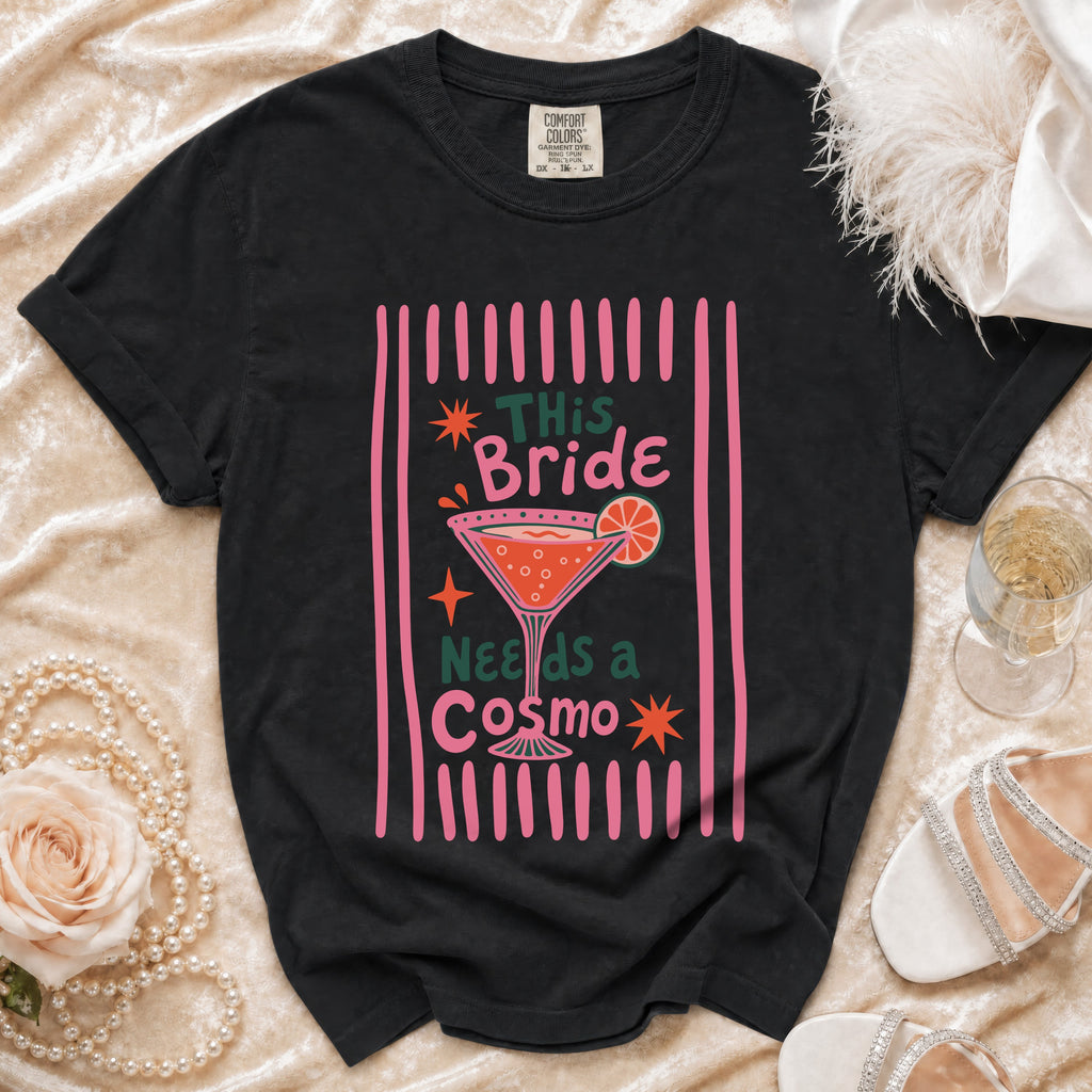 Black t-shirt with "This Bride Needs a Cosmo" graphic and cocktail illustration.