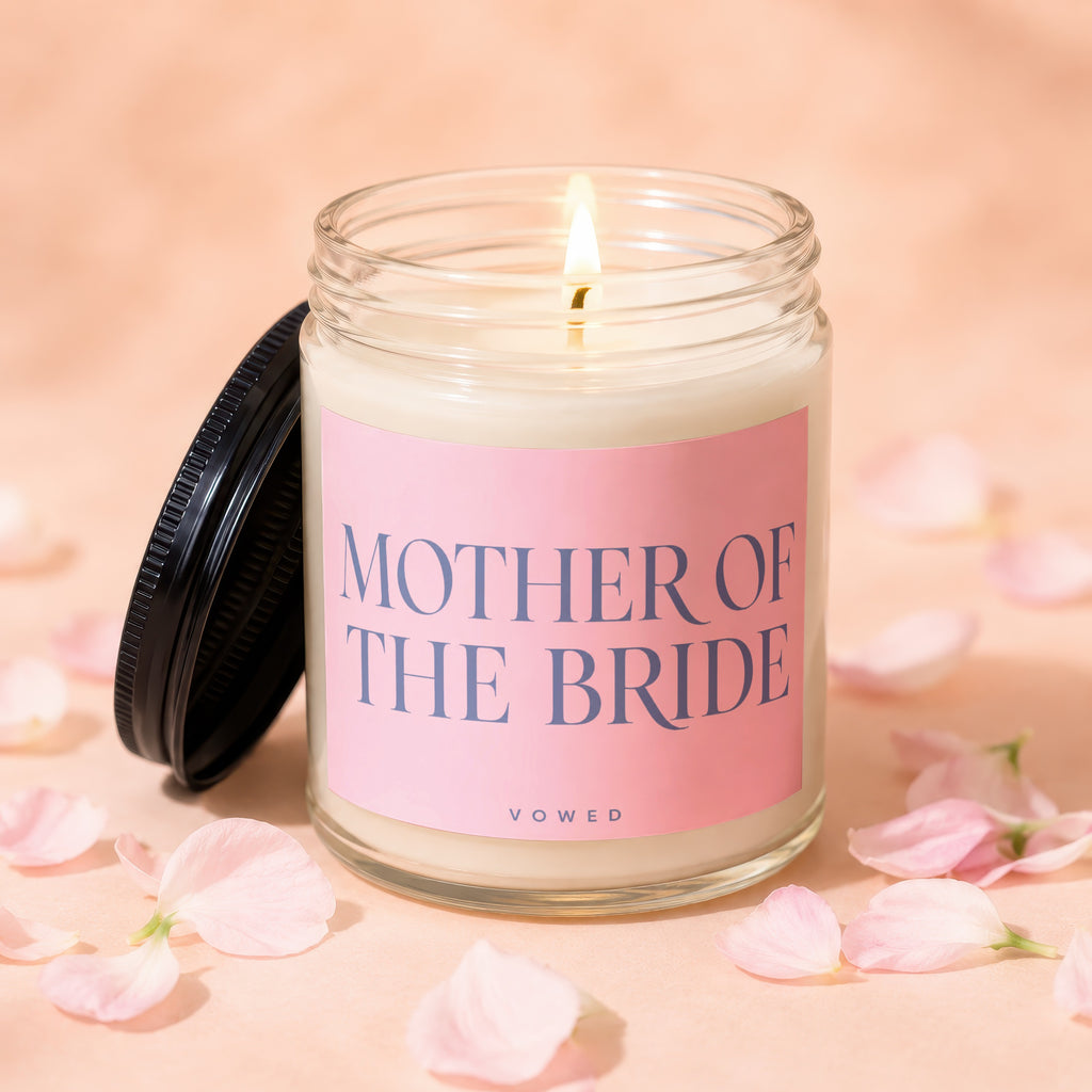 Glass candle with pink label reading "MOTHER OF THE BRIDE" surrounded by flower petals.