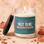 Glass candle with lit wick and label reading "Saved For You: Next to Me Maid of Honor Spot Vowed."