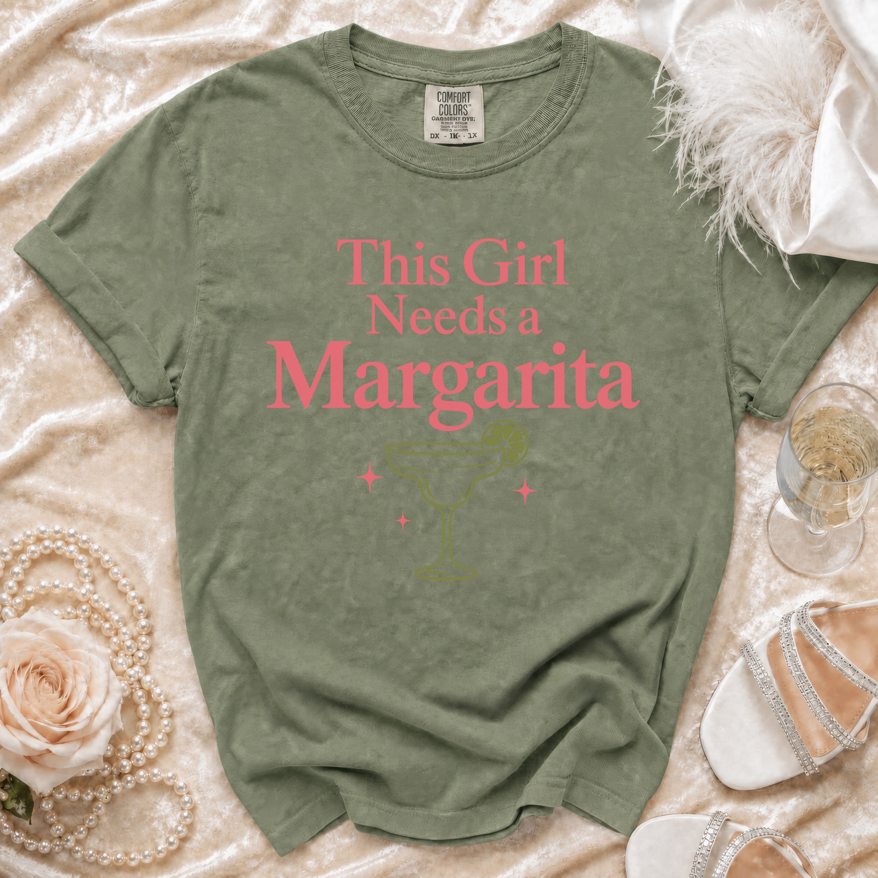 Green t-shirt with pink text "This Girl Needs a Margarita" and margarita graphic.