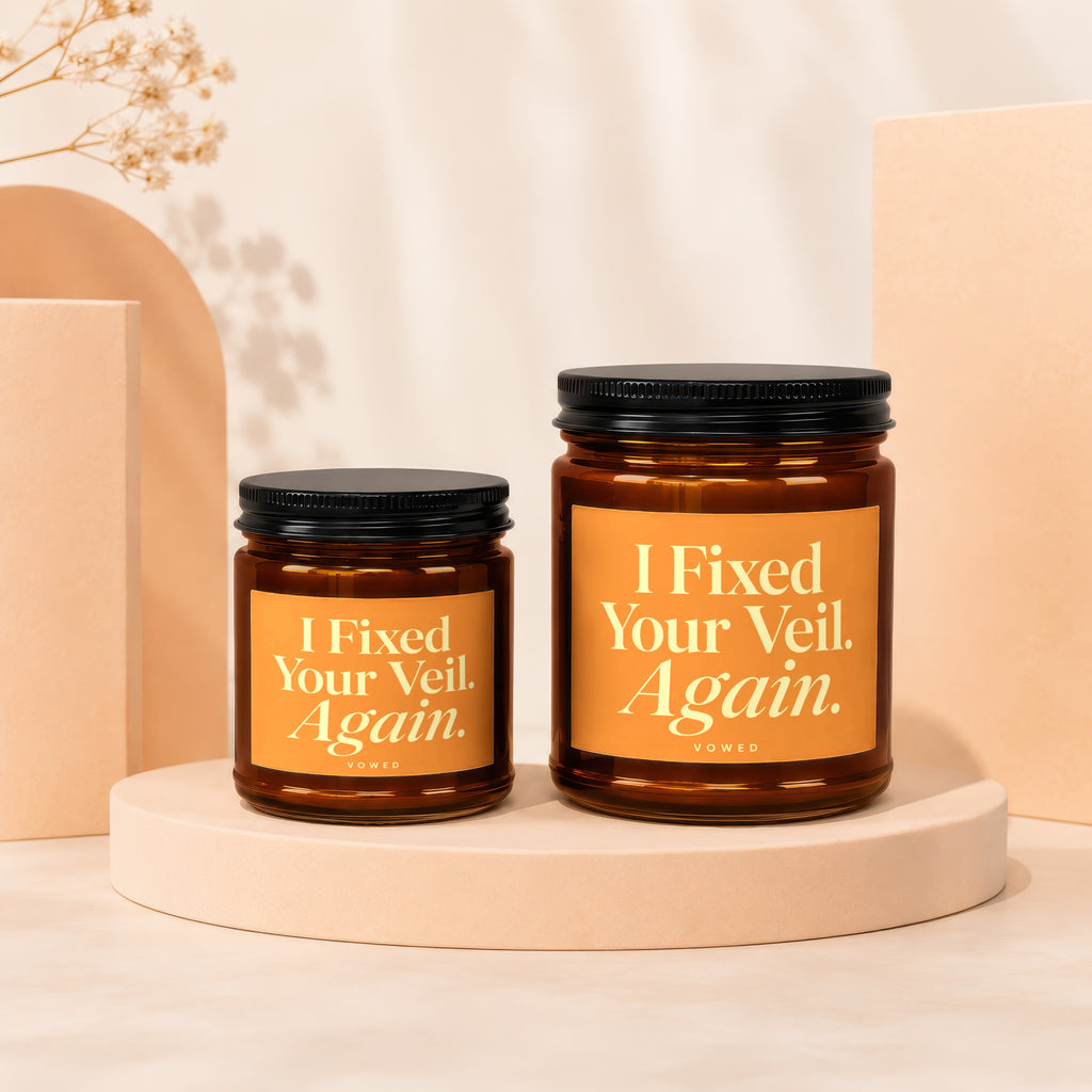 Two amber glass candles with "I Fixed Your Veil. Again." text on labels.