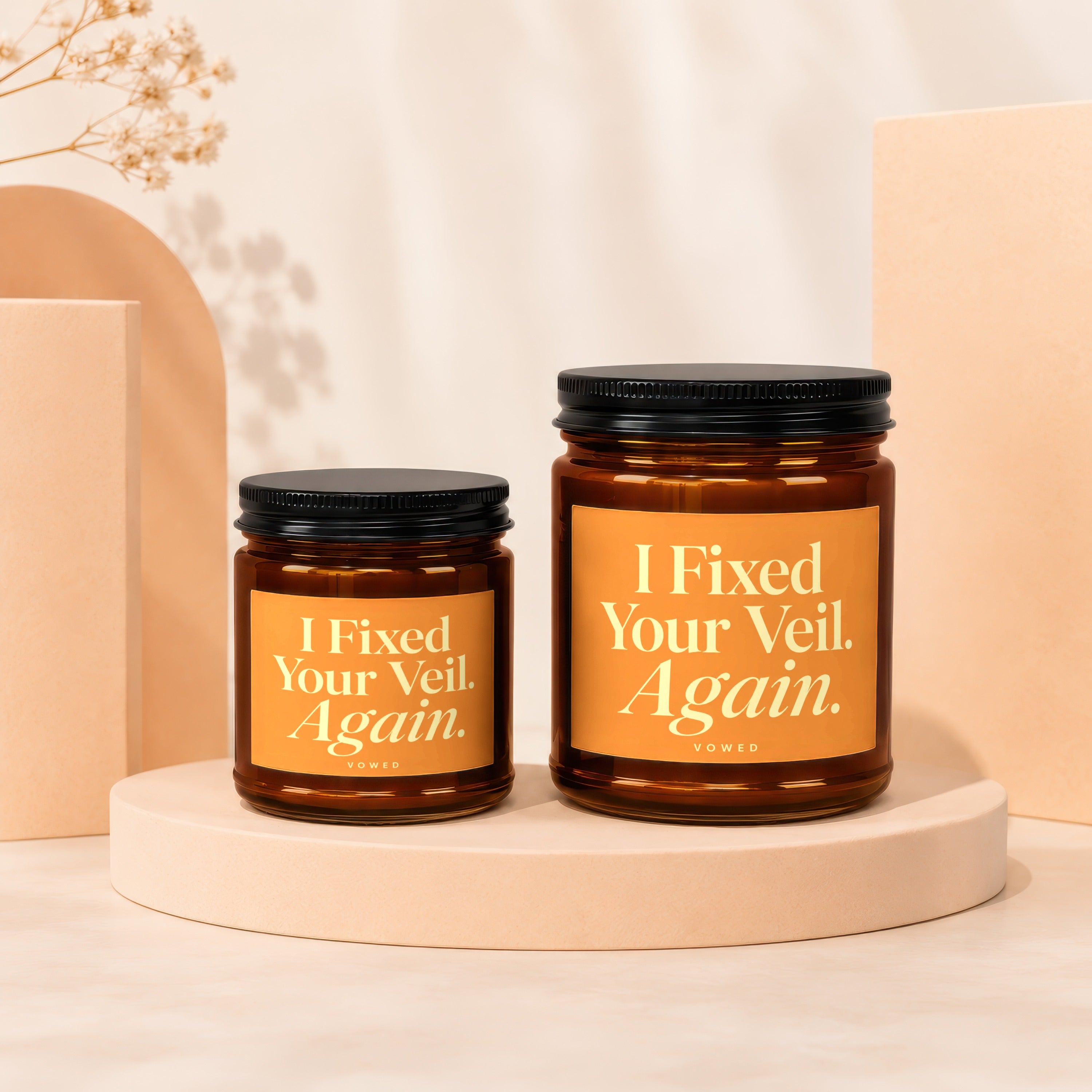 Two amber glass candles with "I Fixed Your Veil. Again." text on labels.