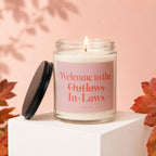 Glass jar candle with pink label reading "Welcome to the Outlaws In-Laws"