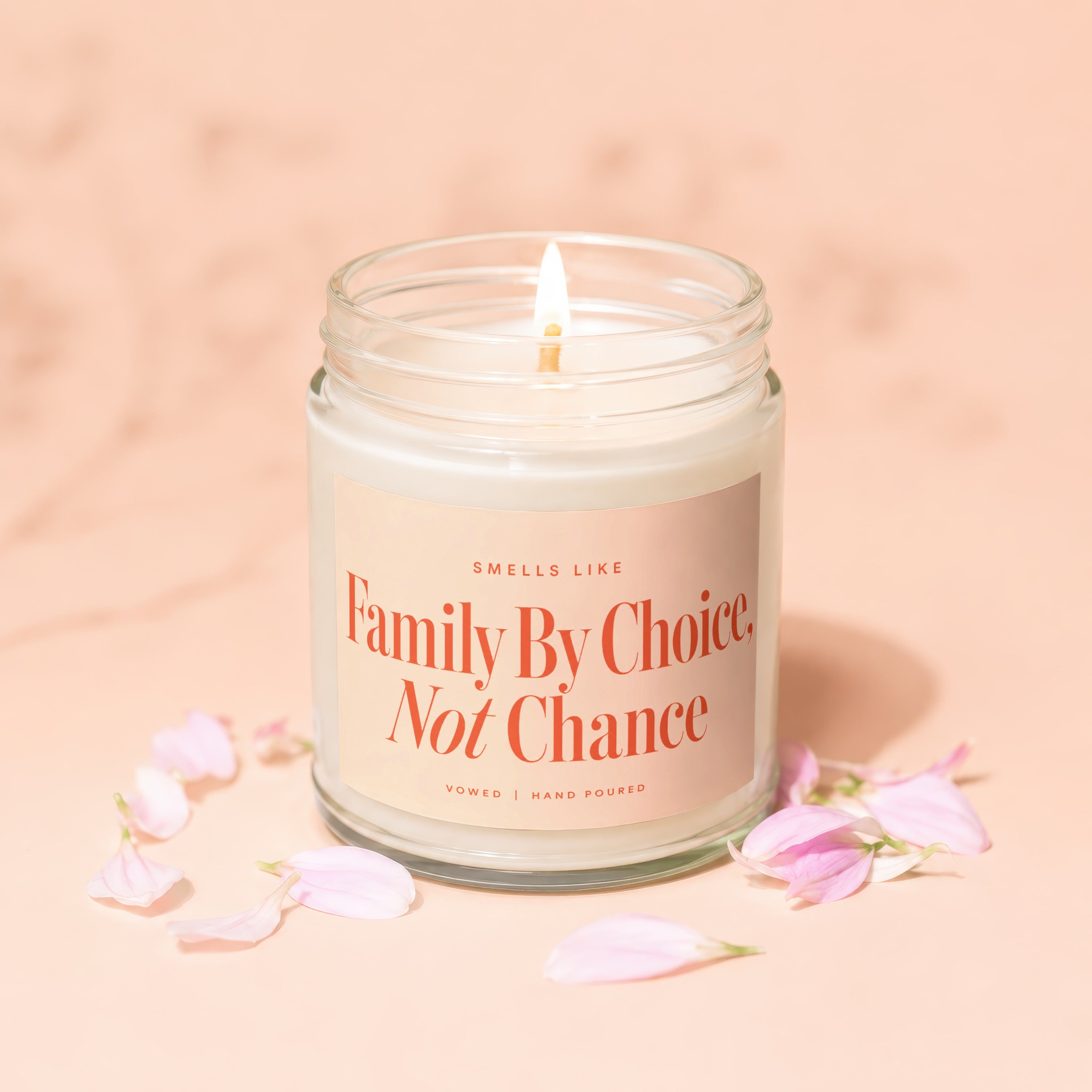 Candle with lit wick and label reading "Smells like Family by Choice, Not Chance."