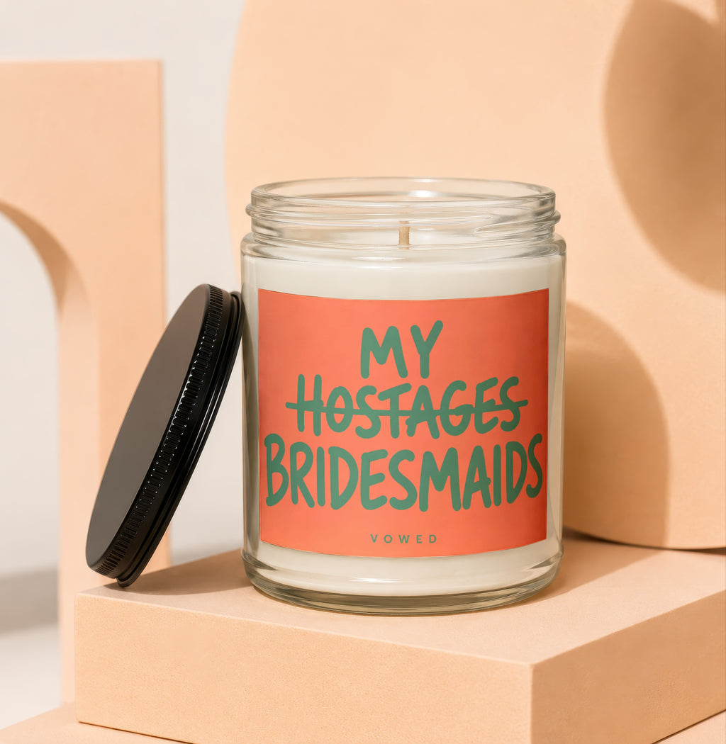 Glass candle with "My Hostages Bridesmaids" text on coral label.