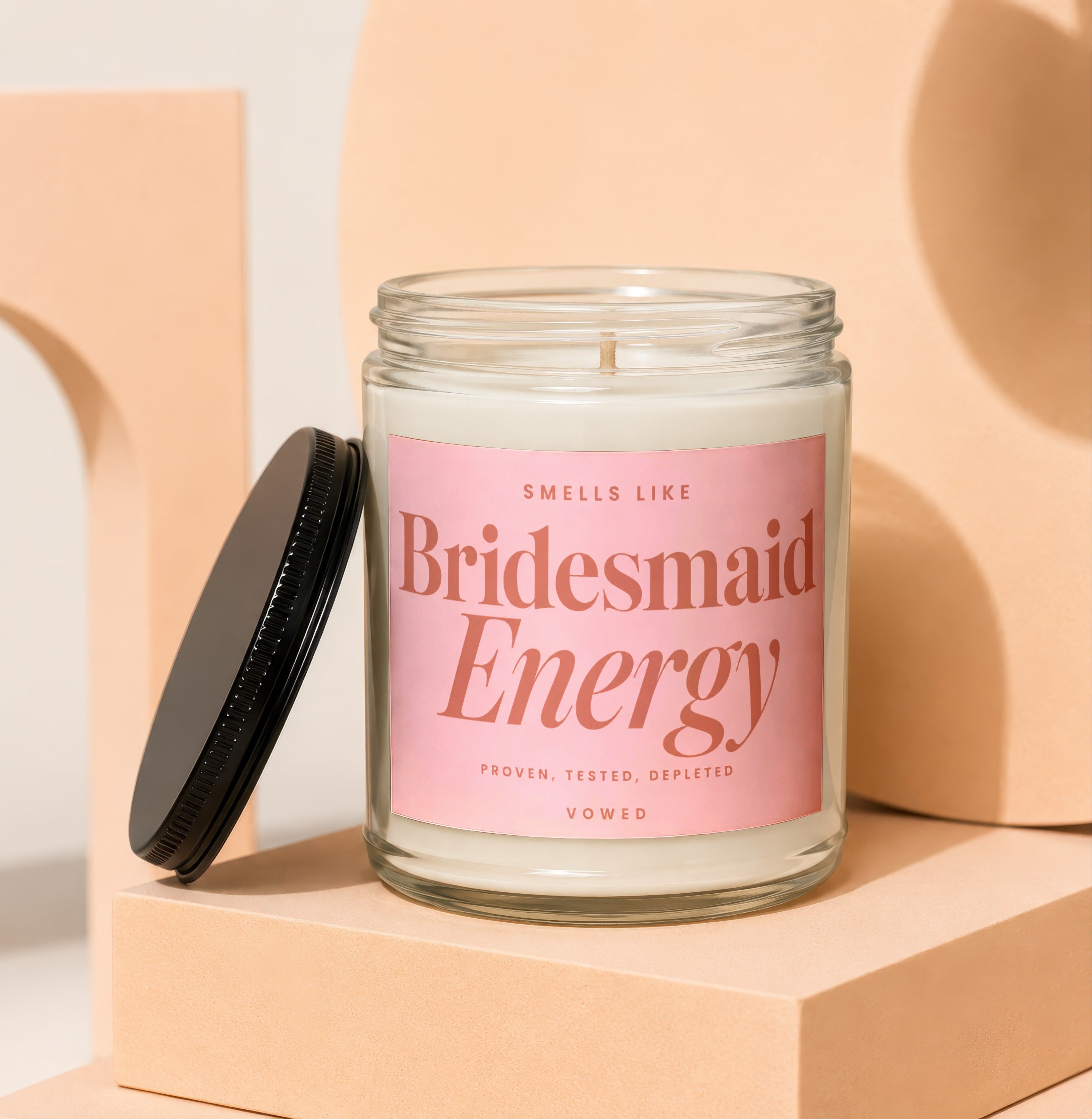 Glass candle with pink label reading "Smells Like Bridesmaid Energy"