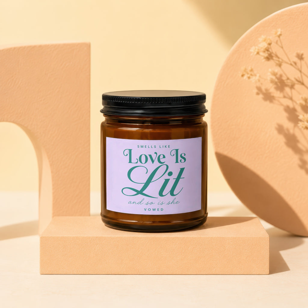 Amber candle with label that reads "Smells Like Love Is Lit and so is she VOWED".