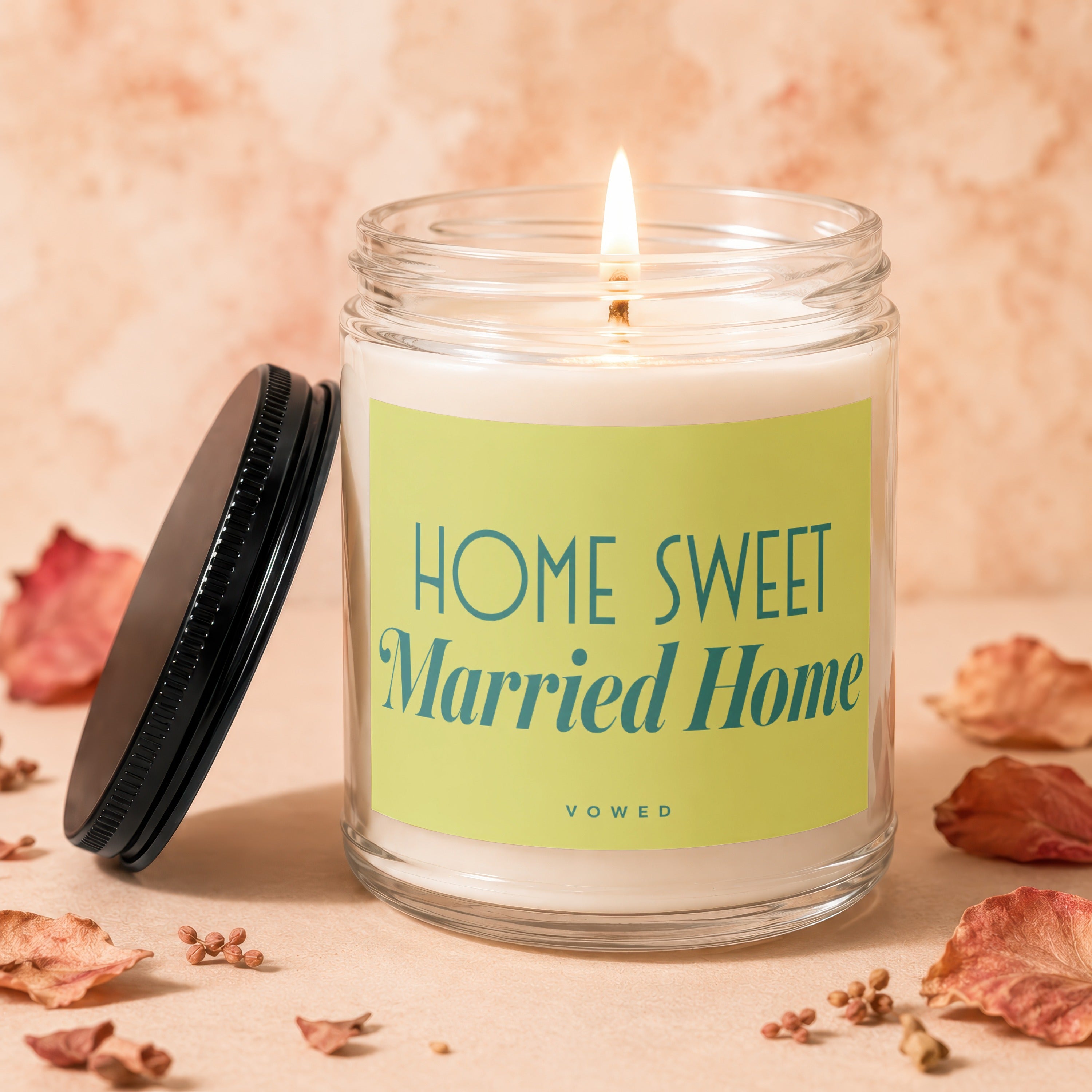 Glass candle burning with "HOME SWEET Married Home" slogan on label.