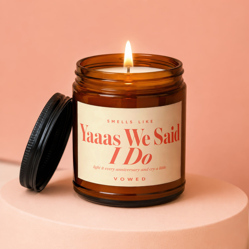 Amber jar candle with lid off reads "Yaaas We Said I Do".