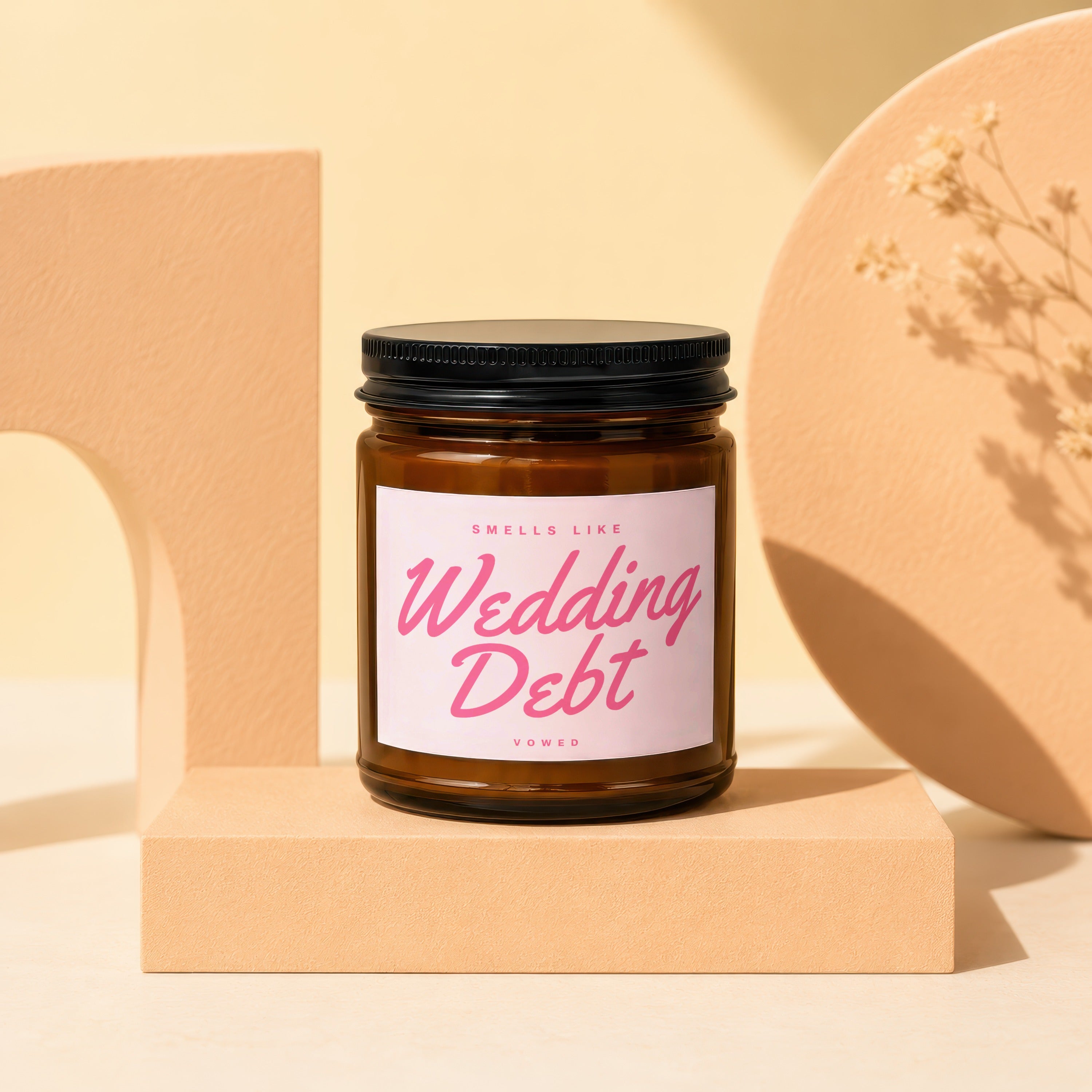 Amber jar candle labeled "Smells Like Wedding Debt".