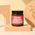 Brown glass candle with pink label reading "Coven Attendee Coordinator".