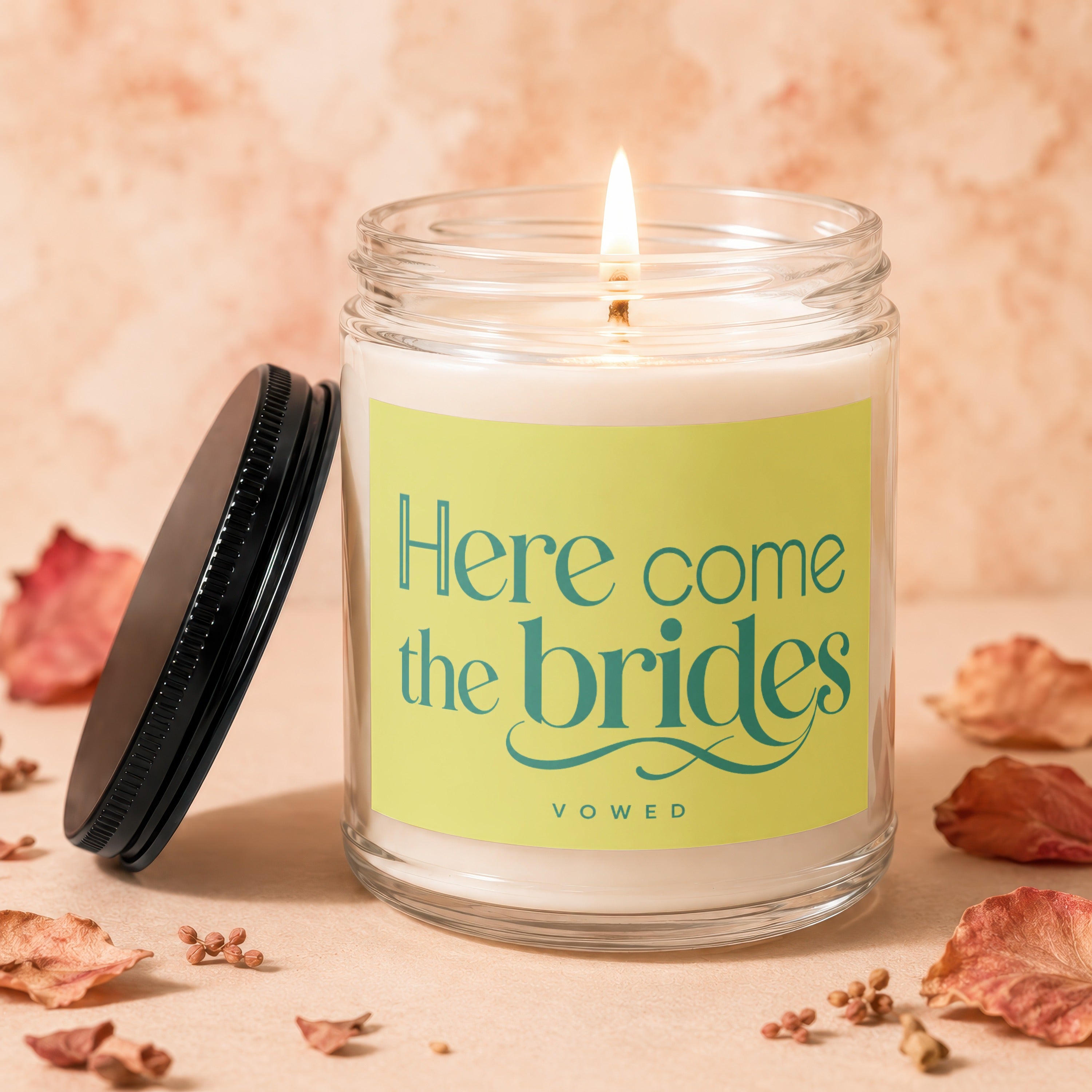 Lit jar candle with "Here come the brides" text on a pale yellow label.