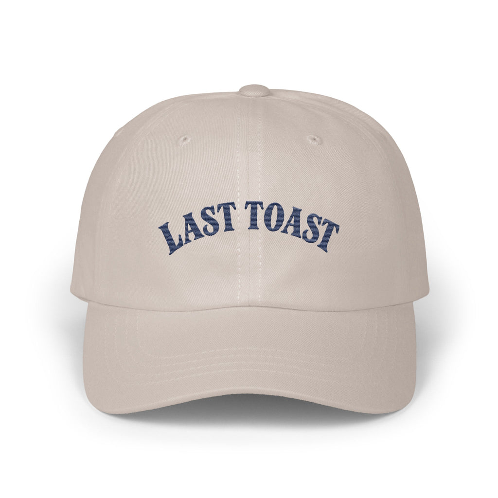 Light tan baseball cap with "LAST TOAST" embroidered in navy blue.