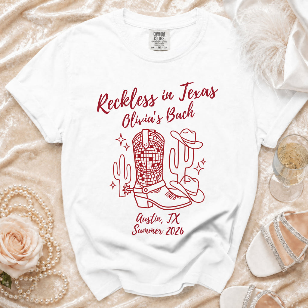 White t-shirt with "Reckless in Texas Olivia's Bach Austin, TX Summer 2026" in red.