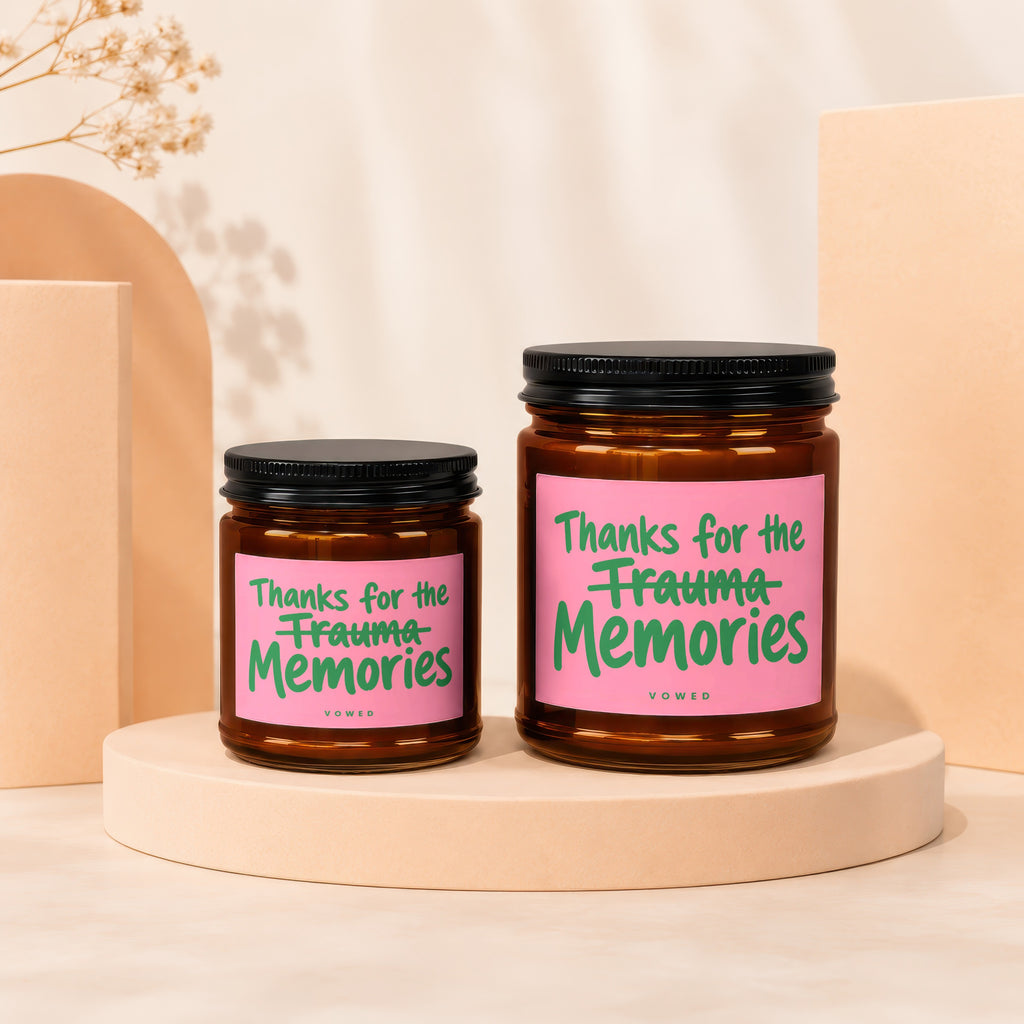 Two amber jars with candles and pink labels reading "Thanks for the Trauma Memories"