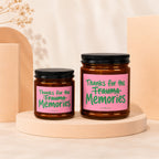 Two amber jars with candles and pink labels reading "Thanks for the Trauma Memories"