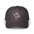 A dark charcoal baseball cap featuring the embroidered white text Wild Wild centered on the front panels.