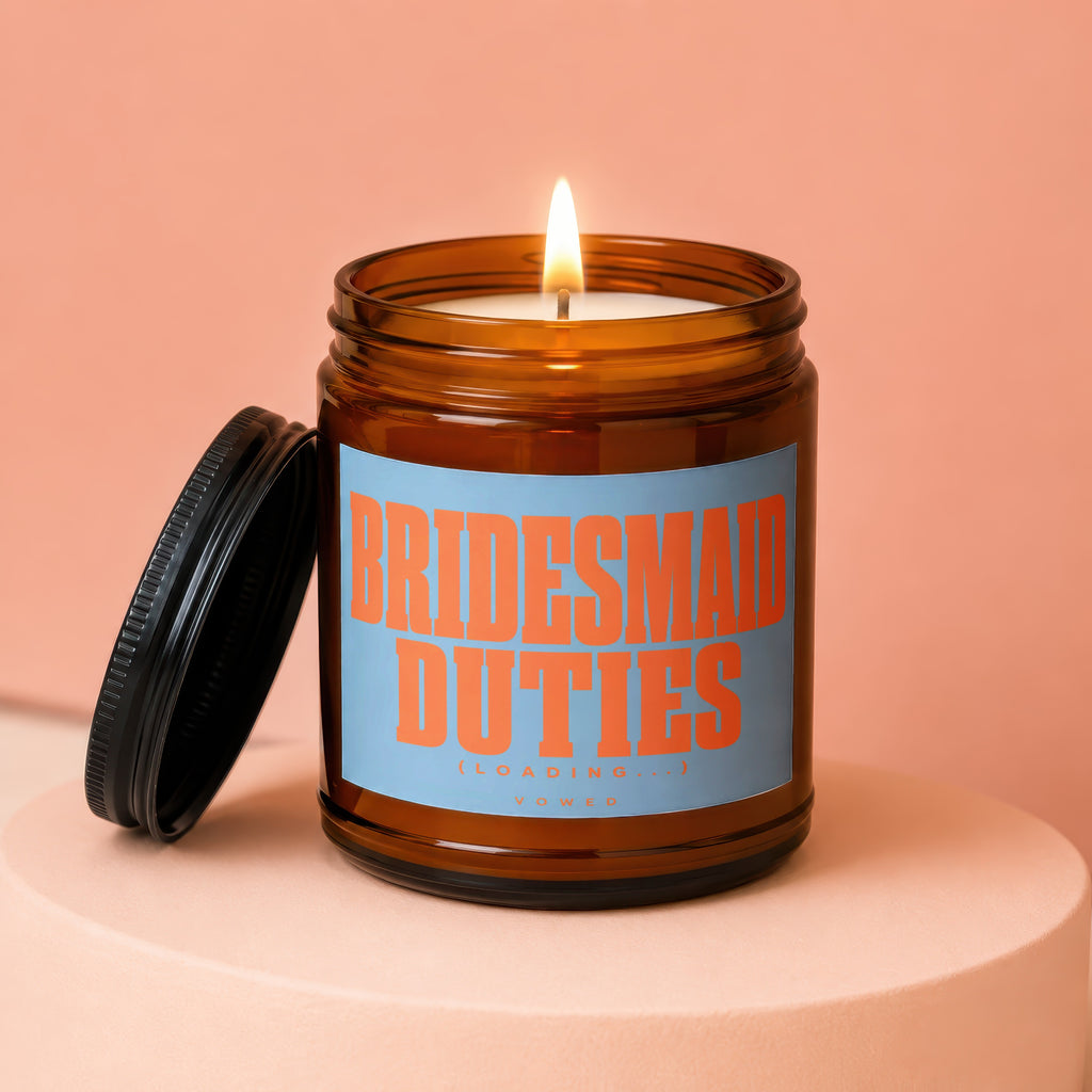 Amber jar candle with lid off, reads "Bridesmaid Duties (loading...) Vowed."
