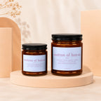 Two amber glass candles with black lids, labeled "matron of honor".