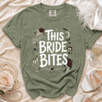 Sage green t-shirt with white "This Bride Bites" text and gothic wedding graphics.