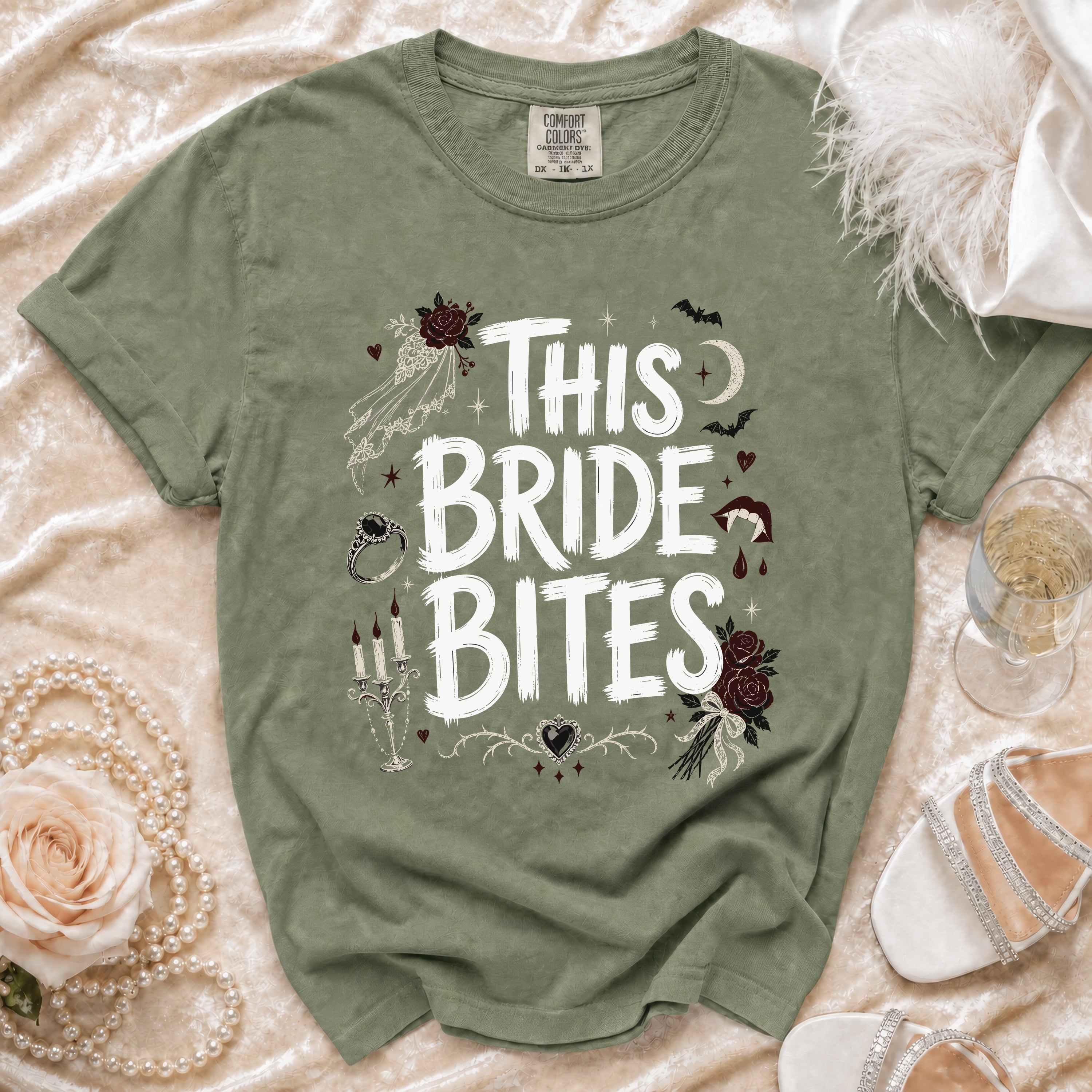 Sage green t-shirt with white "This Bride Bites" text and gothic wedding graphics.