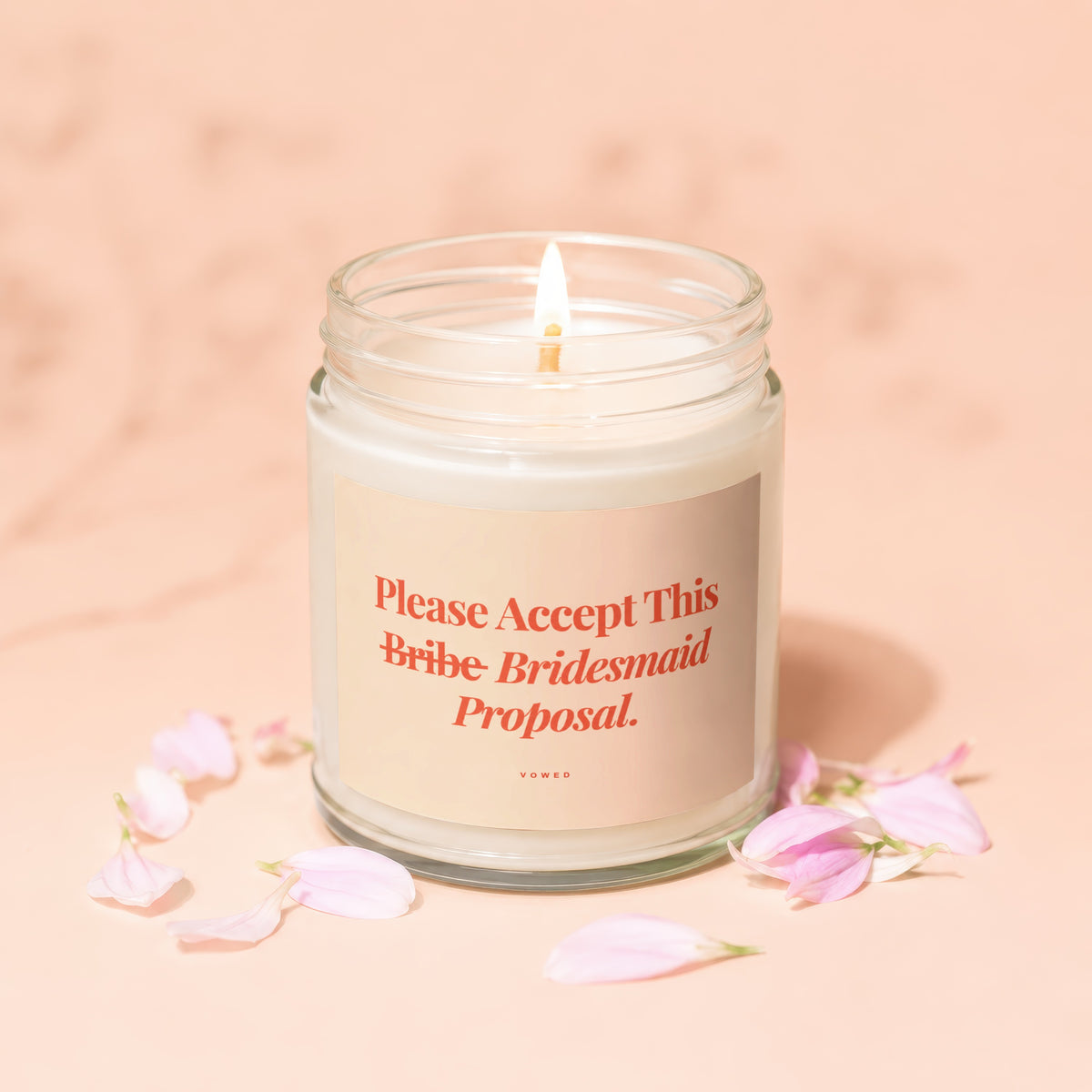 Candle with "Please Accept This Bridesmaid Proposal." text surrounded by pink petals.