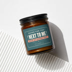Amber candle in jar with dark lid, teal label reads "NEXT TO ME MAID OF HONOR SPOT".