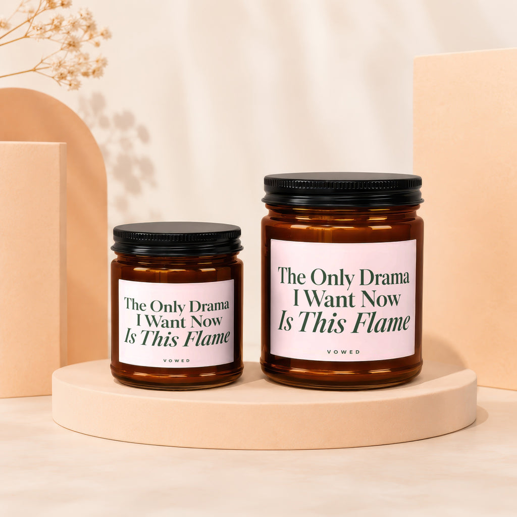 Two amber glass candles with pink labels reading "The Only Drama I Want Now Is This Flame".