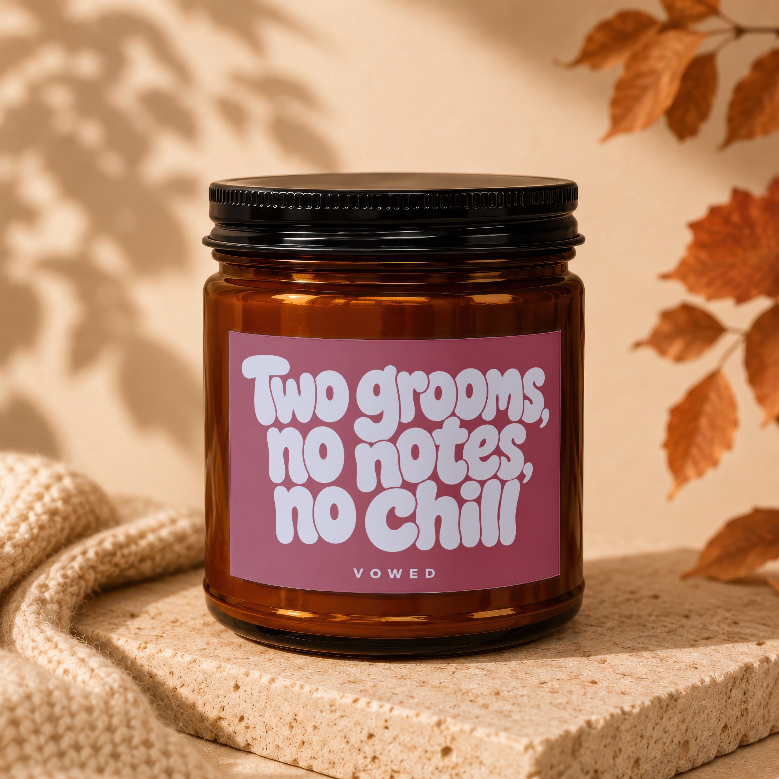 Amber jar candle with pink label reading "Two grooms, no notes, no chill"