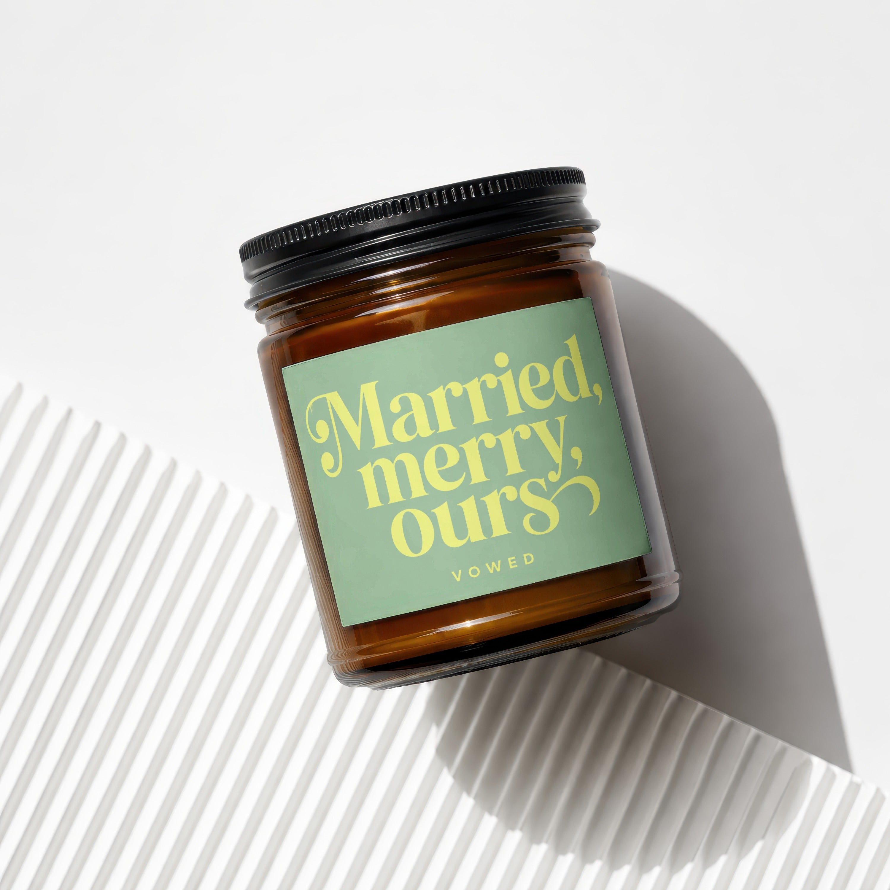 Amber jar candle with green label reading "Married, merry, ours VOWED".