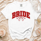 White t-shirt with red "BRIDE" text, bow, and stars graphic.
