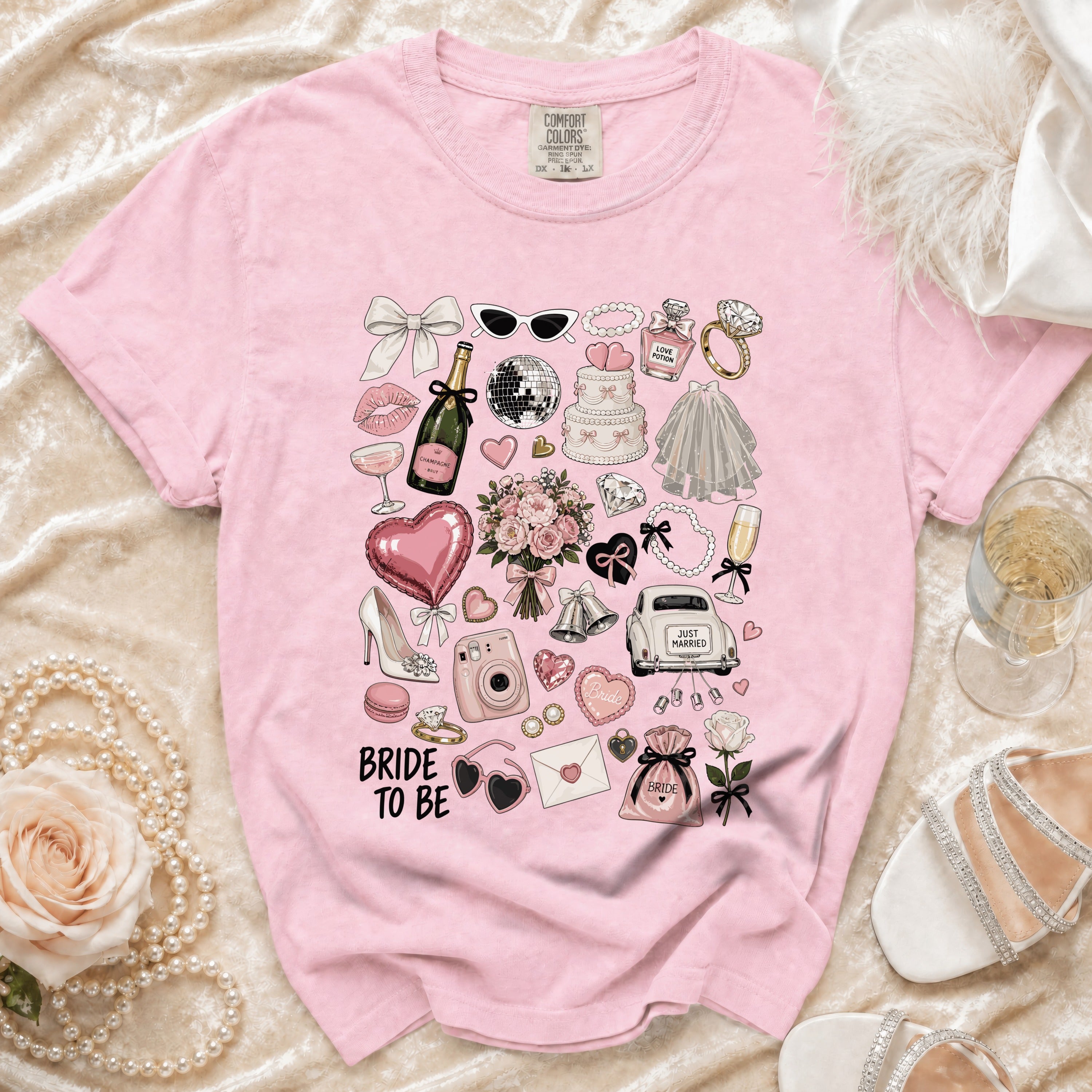 Pink t-shirt with "Bride to Be" and wedding-themed graphics including a cake, champagne, and car.