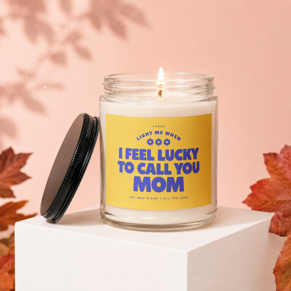 Glass jar candle with yellow label reading "Light me when I feel lucky to call you Mom."