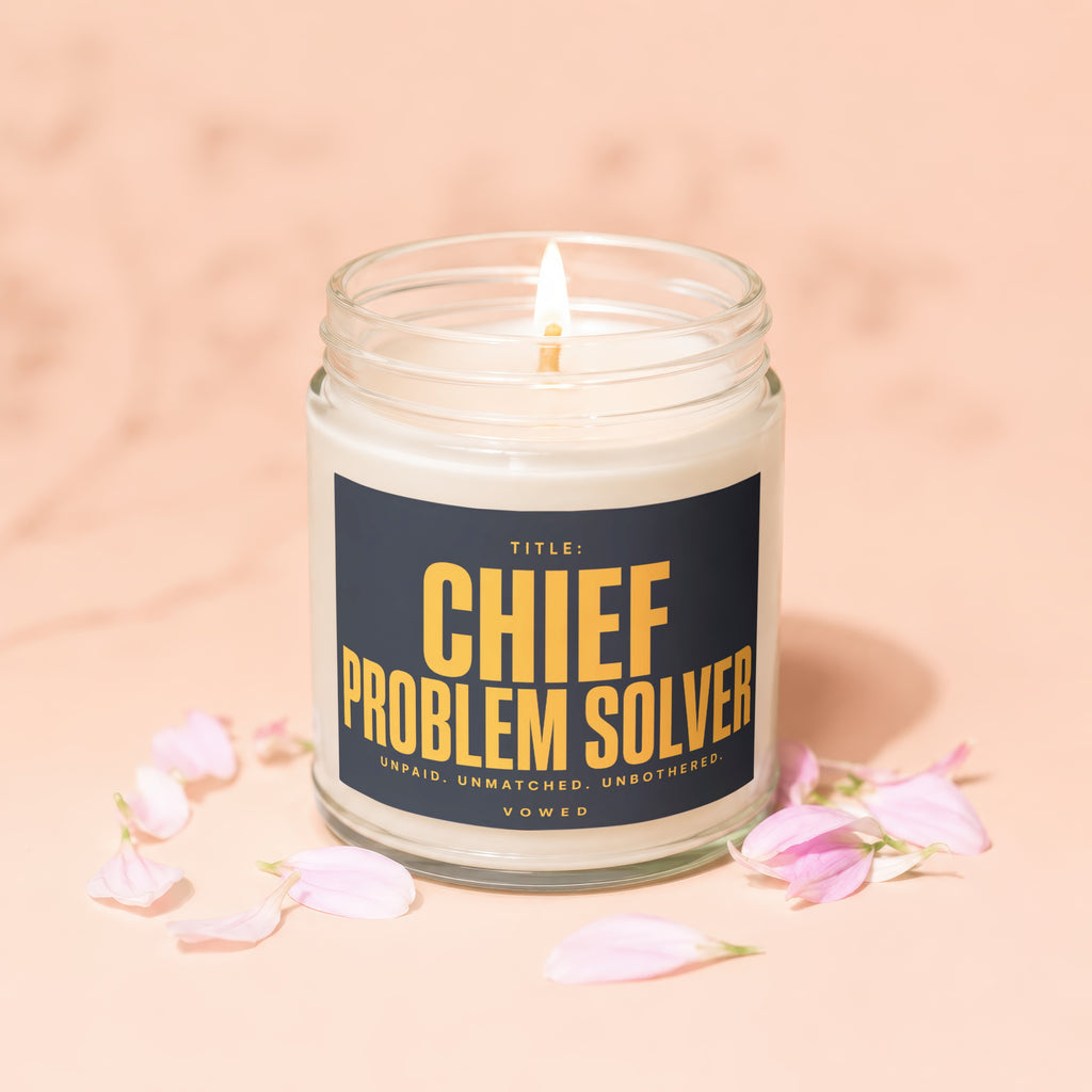 Lit candle in a jar with the label "Chief Problem Solver Vowed Unpaid. Unmatched. Unbothered."
